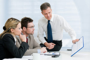 Three people sitting around a table looking at a document.